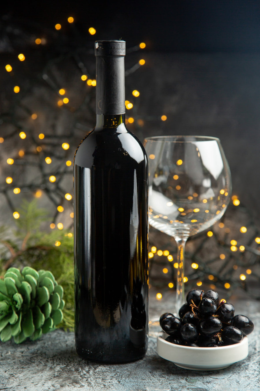 Wine bottle, glass, and grapes on a table with a festive background